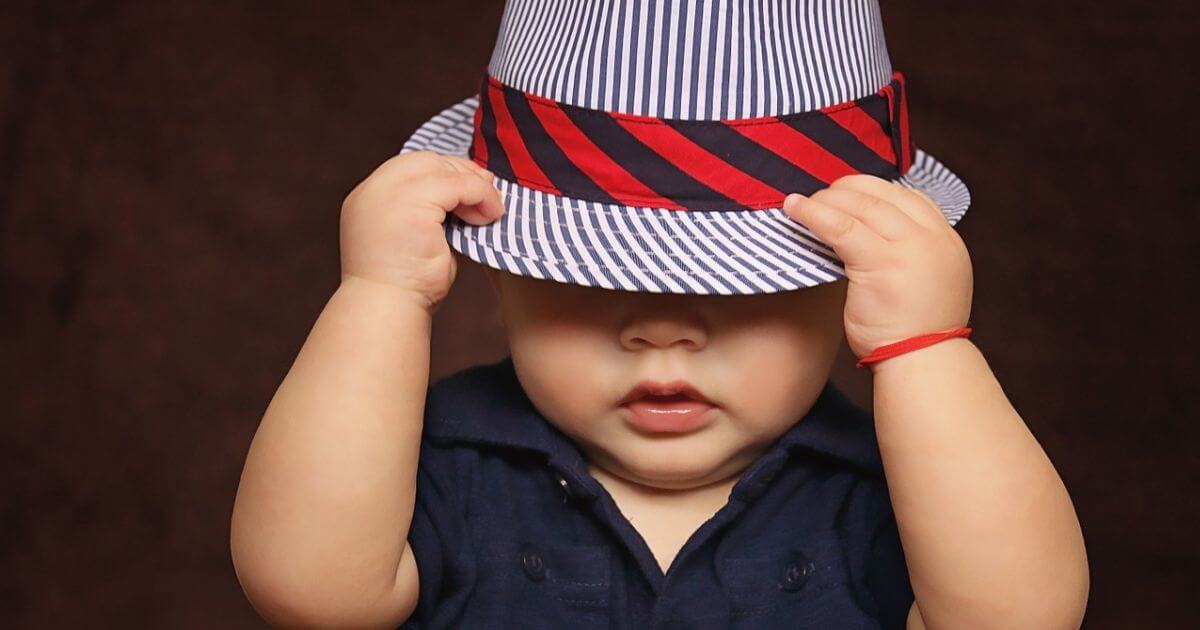 帽子を目深にかぶる赤ちゃんの写真